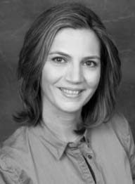 The image shows a woman with short hair smiling at the camera.