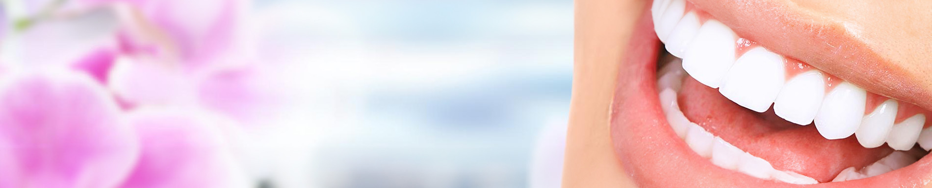 The image shows a smiling woman with white teeth against a blurred background featuring cherry blossoms.