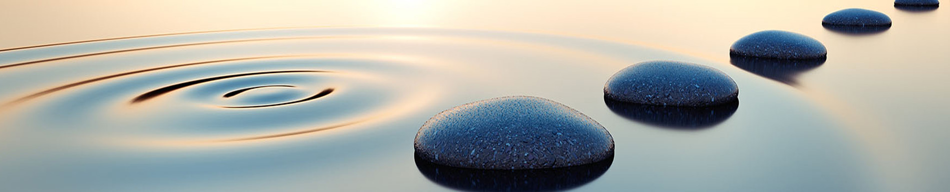 The image shows a tranquil scene with a body of water reflecting the sky at sunset, featuring ripples and three rocks resting on the surface near the center of the frame.