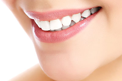 The image features a close-up view of a person's smile showcasing white teeth against a neutral background, emphasizing oral hygiene and dental care.