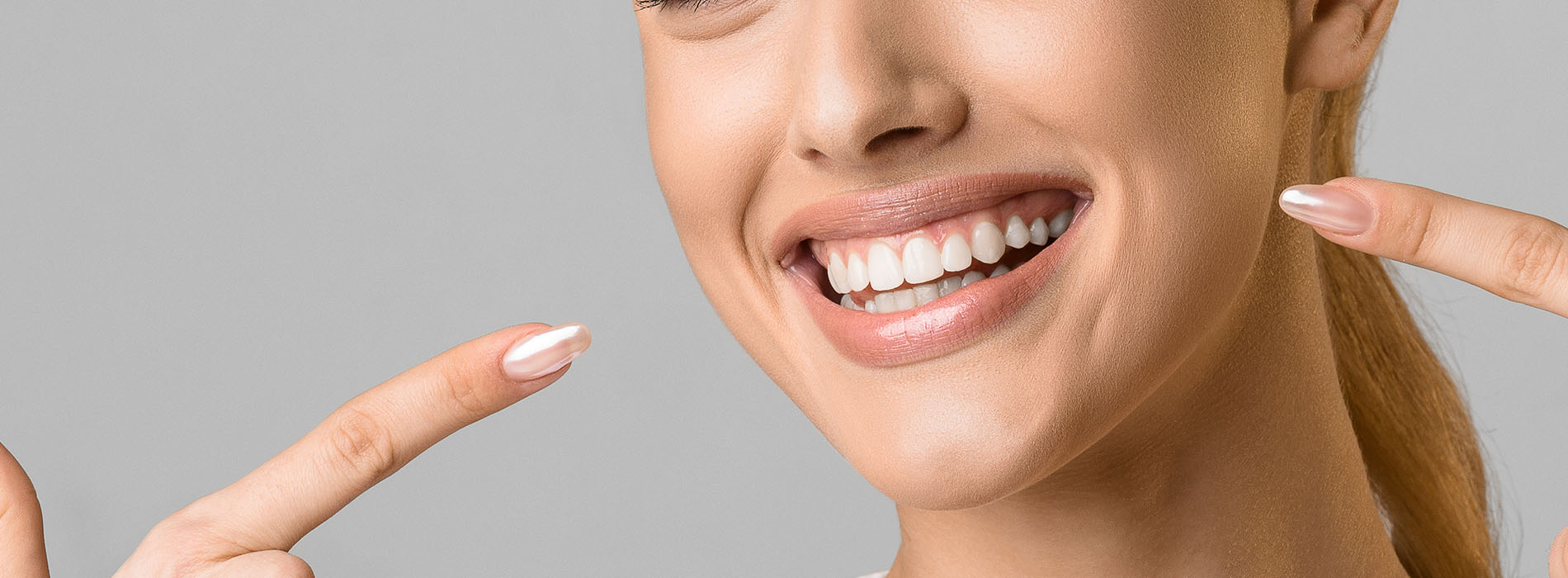 Woman with radiant smile, showing teeth, against neutral background.